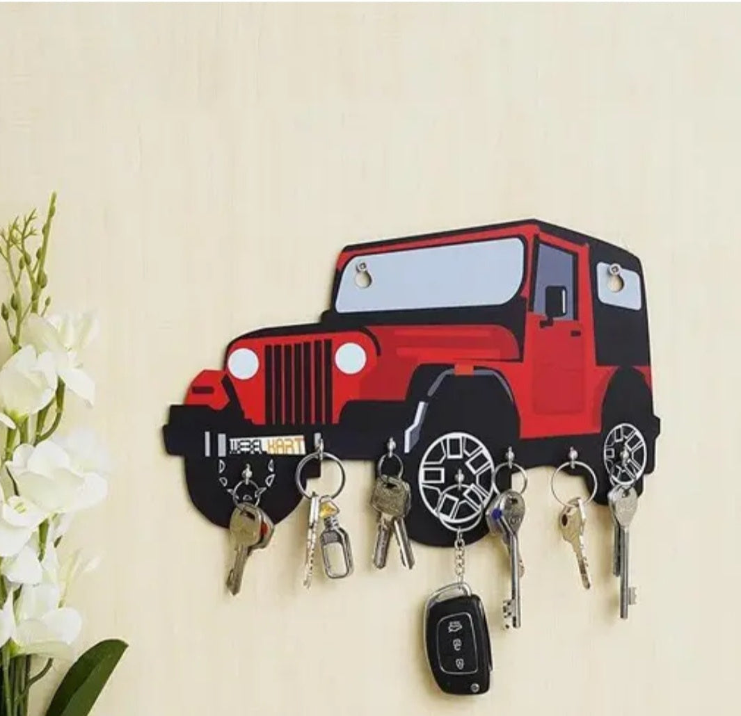 Key holder shaped like a red jeep with keys attached on a beige wall.